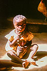 Young girl siting in sunshine & eating monkey bread fruit