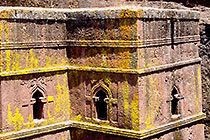 wall with yellow lichens & window ogives & church roof