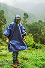 Petra w blue pancho walking on wet grass