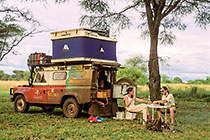 Petra & Paul eating aperitive at back landy( RL) w tent at campsite + campfire