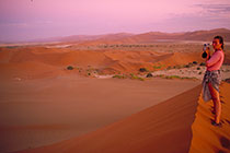 Petra filming on dune ridge + desert + red sand dunes at dusk