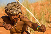 bushman hunting with bow & arows on red sand dunes