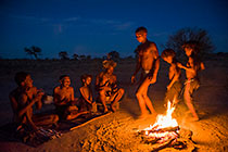 bushman sitting & dancing around the fire at dusk