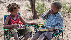 bushman children eating stitting around camp fire