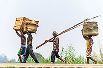 people walking carrying boxes on head