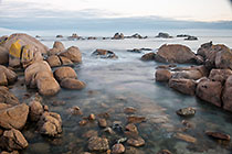 boulders in sea with smooth waves