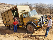 Lisa watching Sedney removing 5 T cement bags from 4x4 truck broken down on plot access road