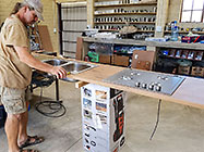 Paul installing double sink and gas stove on studio kitchen counter