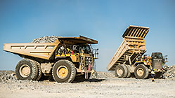 90 T trucks offloading rocks on top of waste pile