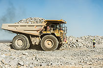 worker & 90 T truck offloading rocks on top of waste pile