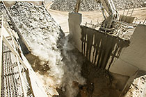 90 T truck offloading graded rocks into crusher