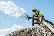 environmental field assistant collecting water sample from cyclone sparyer on tailings