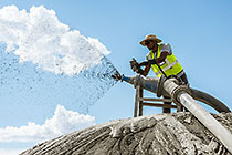 environmental field assistant collecting water sample from cyclone sparyer on tailings