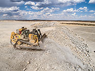 bulldozer levelling rocks on top of waste pile