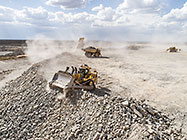 bulldozer & 90 T trucks offloading rocks on top of waste pile