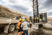 workers repairing drill of drilling machine in pit