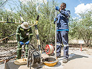 environmental field assistants taking borehole water sample
