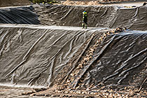 arsenic waste site | workers laying thick plastic lining at bottom of new bassin
