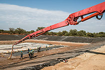 workers laying concrete on top of thick plastic lining in new water bassin