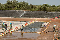 workers laying concrete on top of thick plastic lining in new water bassin