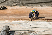 workers laying concrete on top of thick plastic lining in new water bassin