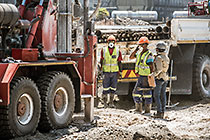 workers drilling borehole near processing plant
