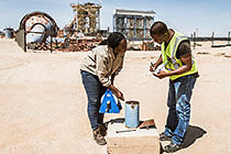 environmental scrientists Kaarina Nkandi & Salatiel taking fresh water sample at boreole