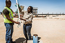 environmental scrientists Kaarina Nkandi & Salatiel taking fresh water sample at boreole