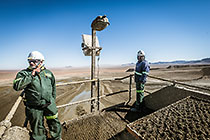 workers at the end of conveyor belt on top of tailings