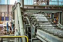 foundry | robot at the end of conveyor belt carrying hot bricks of zinc