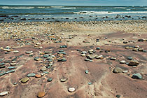 pebbles on red sand coast line