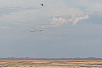 helicopter flying with SkyTEM rig over arid plain