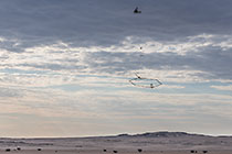 helicopter flying with SkyTEM rig over arid plain