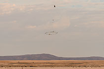 helicopter flying with SkyTEM rig over arid plain