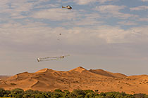 helicopter flying with SkyTEM rig over sand dunes