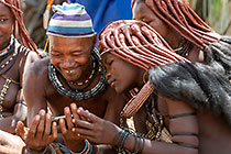 Himba people looking at photos under tree