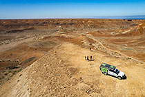 Paul, Lisa, Maria & Chanan on top of hill near ranger-camper & disco in arid valley & canyon landscape