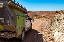 ranger-camper driving on rocky track through arid canyon