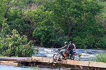motorcycle crossing brocken bridge over river