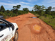 ranger-camper on red soil road with water potholes