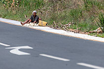 woman drying manioc on side of road