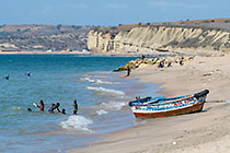children playing in sea near boats & cliffs