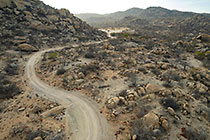 track through granite boulders & cactus-like euphorbia plants on hill at sunrise