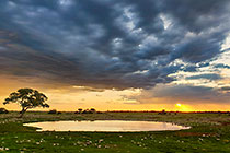 waterhole under stormy clouds at sunset