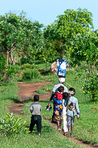 mother carrying baby on back & young girl carrying doll on back