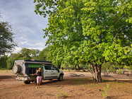 Roberta & ranger camper under green tree at Xmas