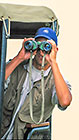 guest watching game through binoculars from game drive vehicule