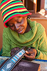 woman sewing beadles on leather belt